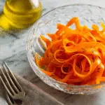 Ribbon Carrot Salad with sesame seeds and herbs on a fresh white plate.